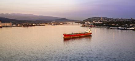 A bulk cargo ship floats in the water at twilight